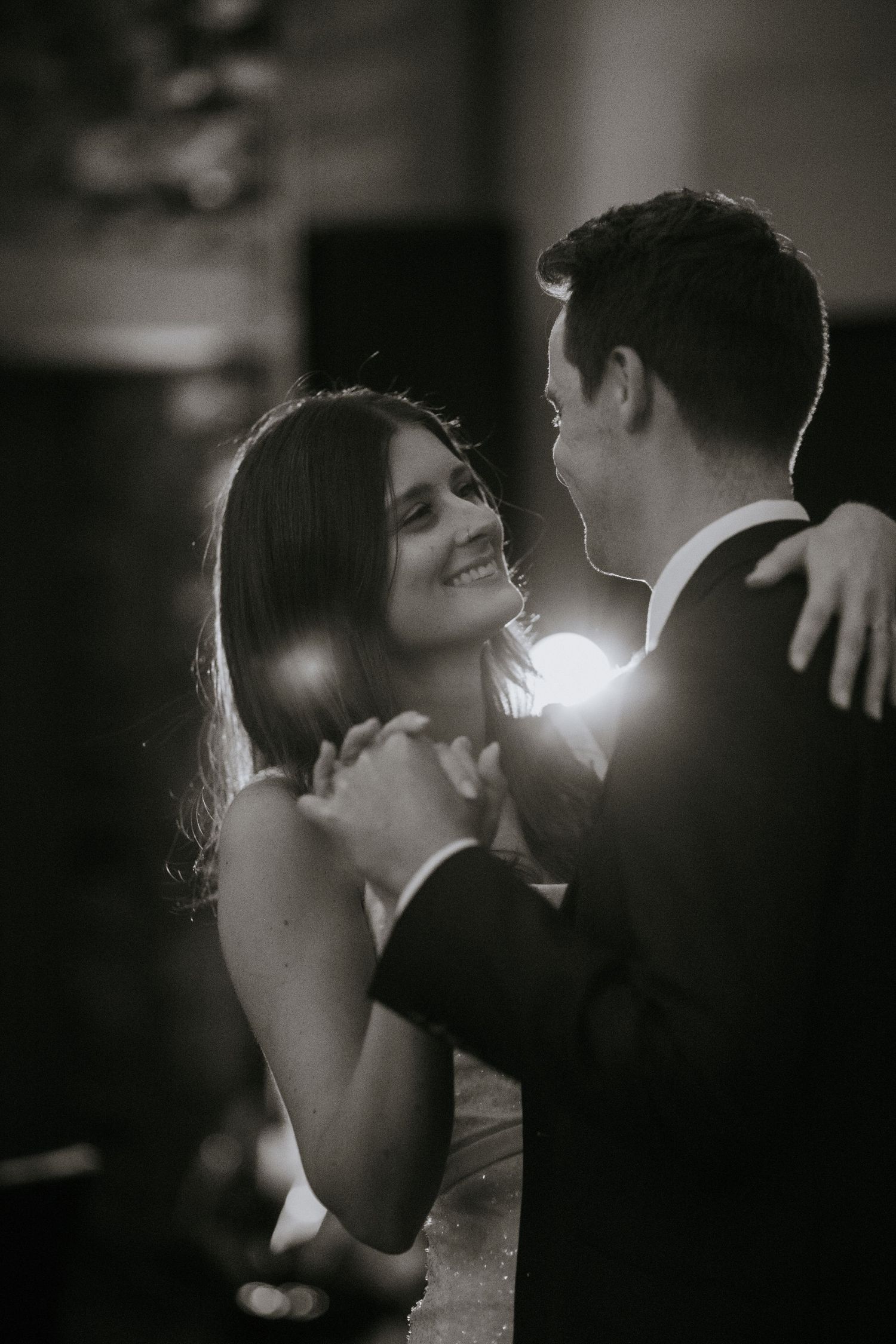 A romantic black and white sequence of a couple sharing an intimate dance moment with dramatic backlighting.