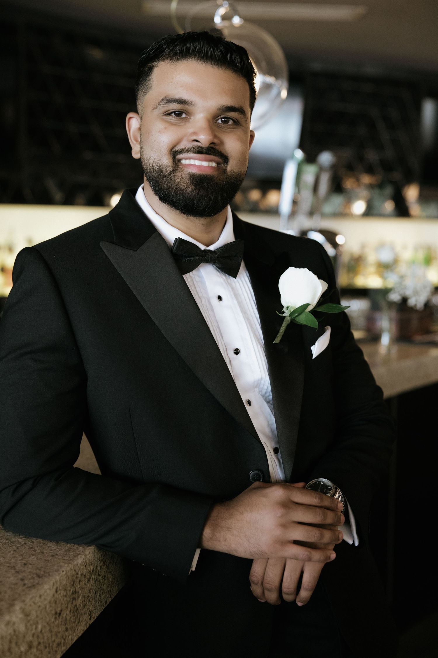 A sequence of photos showing a groom in a classic black tuxedo with a boutonniere.