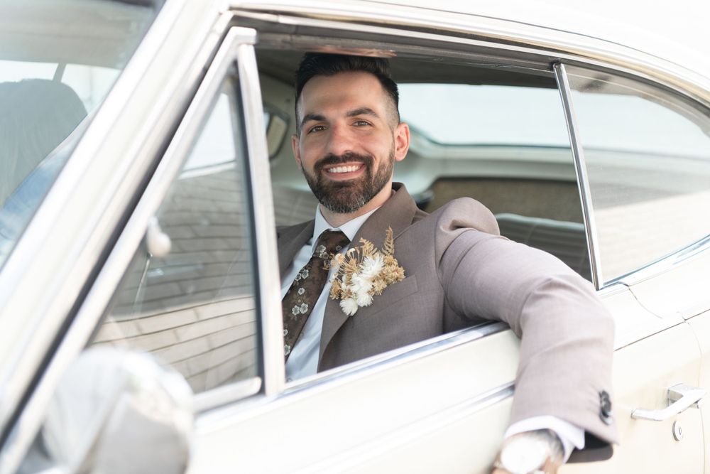 A joyful moment captured through a classic car window on a wedding day.