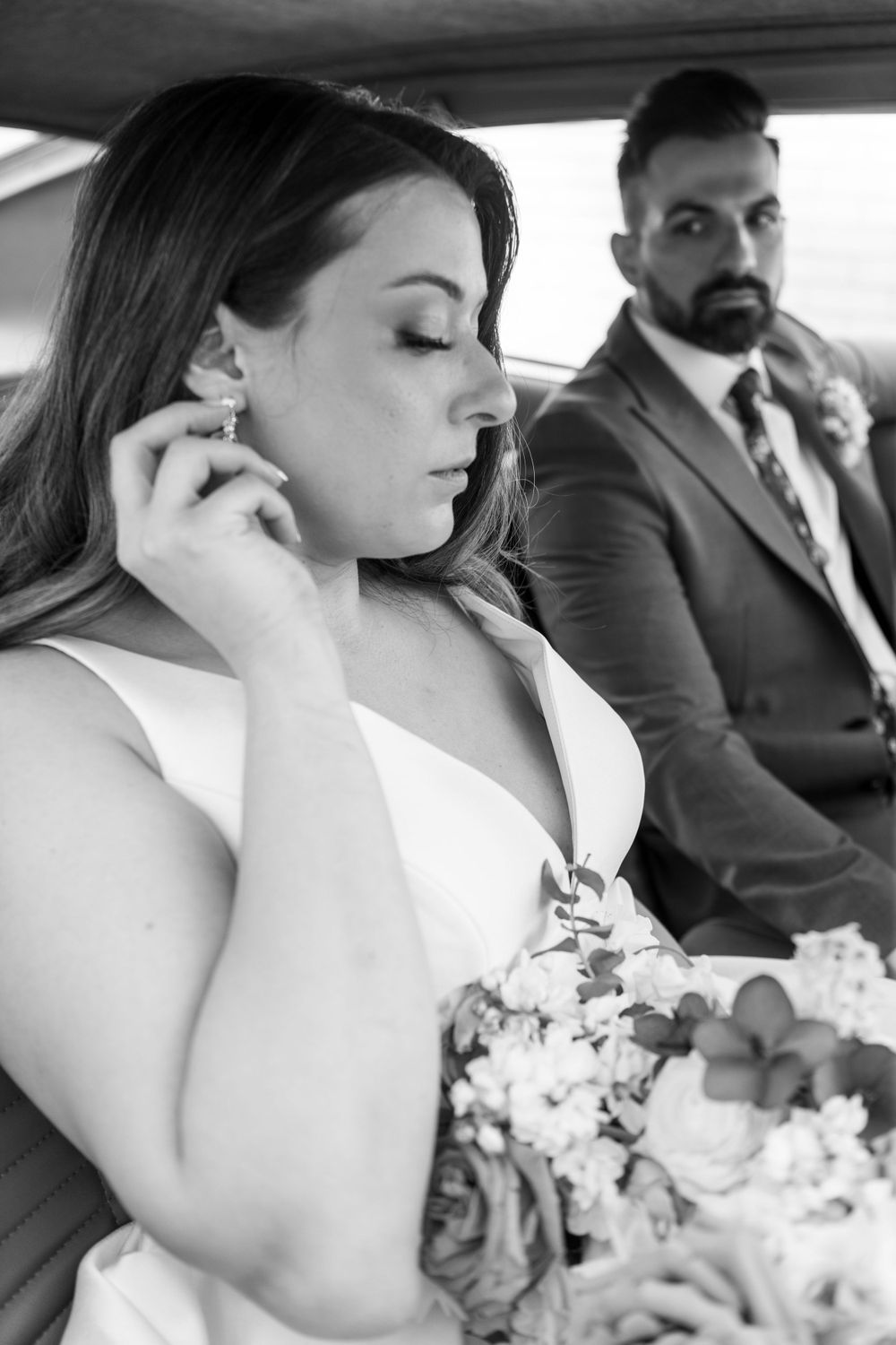A black and white candid moment inside a vintage car on wedding day.