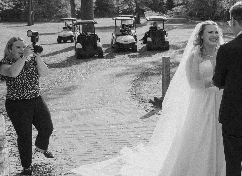 A candid moment at a golf course wedding with a bride in white dress while golf carts are visible in the background.