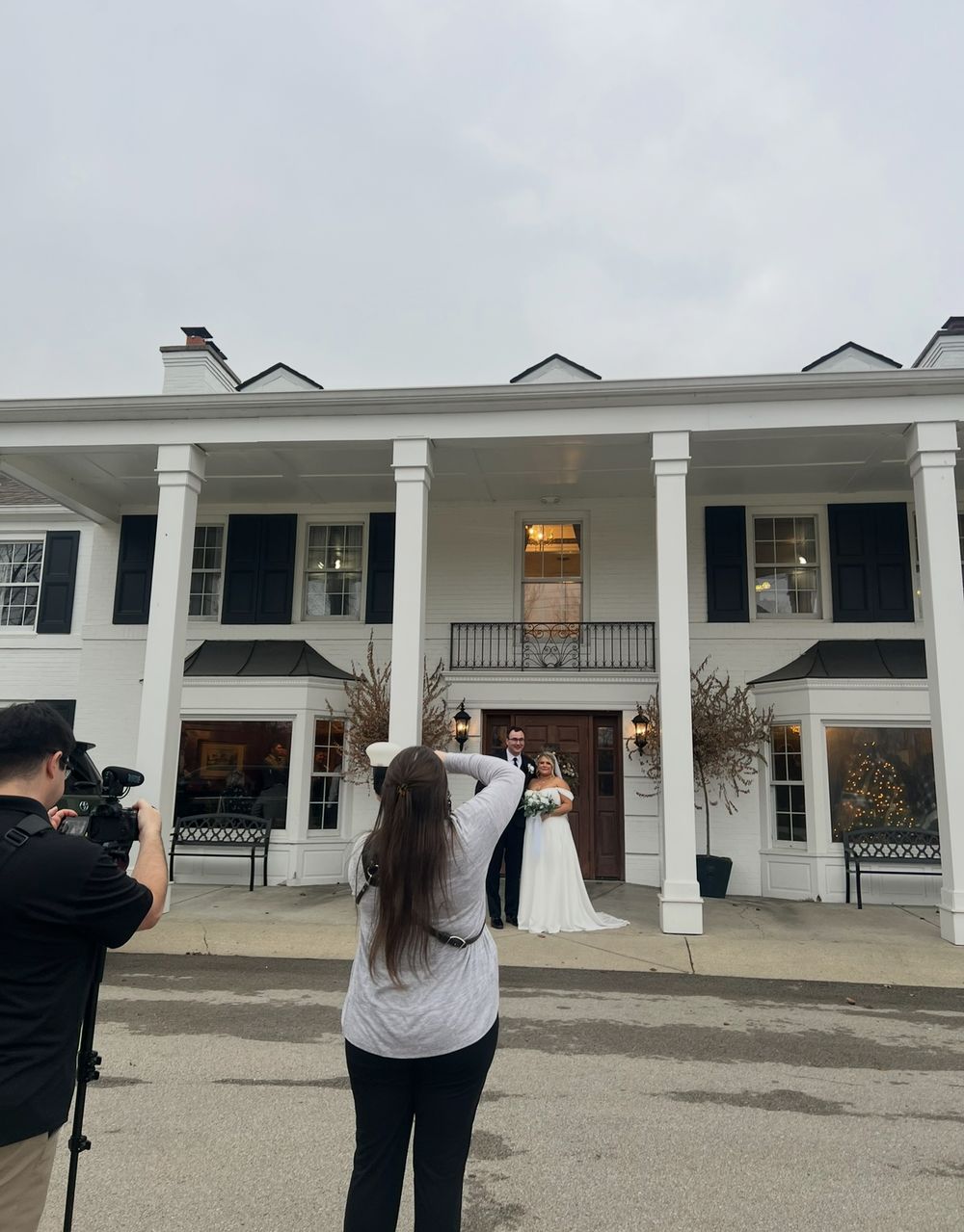Photographer captures an event at a stately white colonial mansion with tall columns and black shutters.