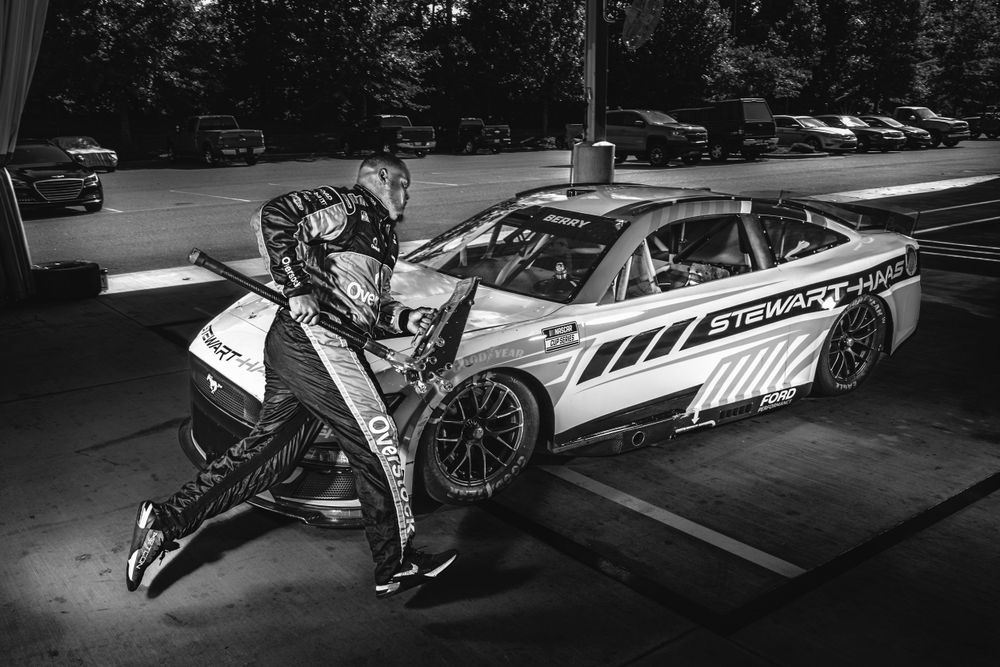 Racing car parts and equipment laid out in dramatic black and white lighting.