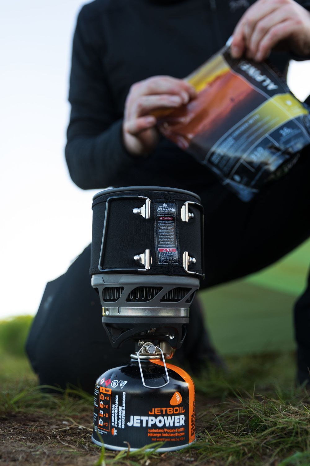 Close-up of a camping stove setup with JetPower fuel canister being installed.