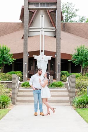 Romantic moment captured outside a modern brick church entrance with landscaping.