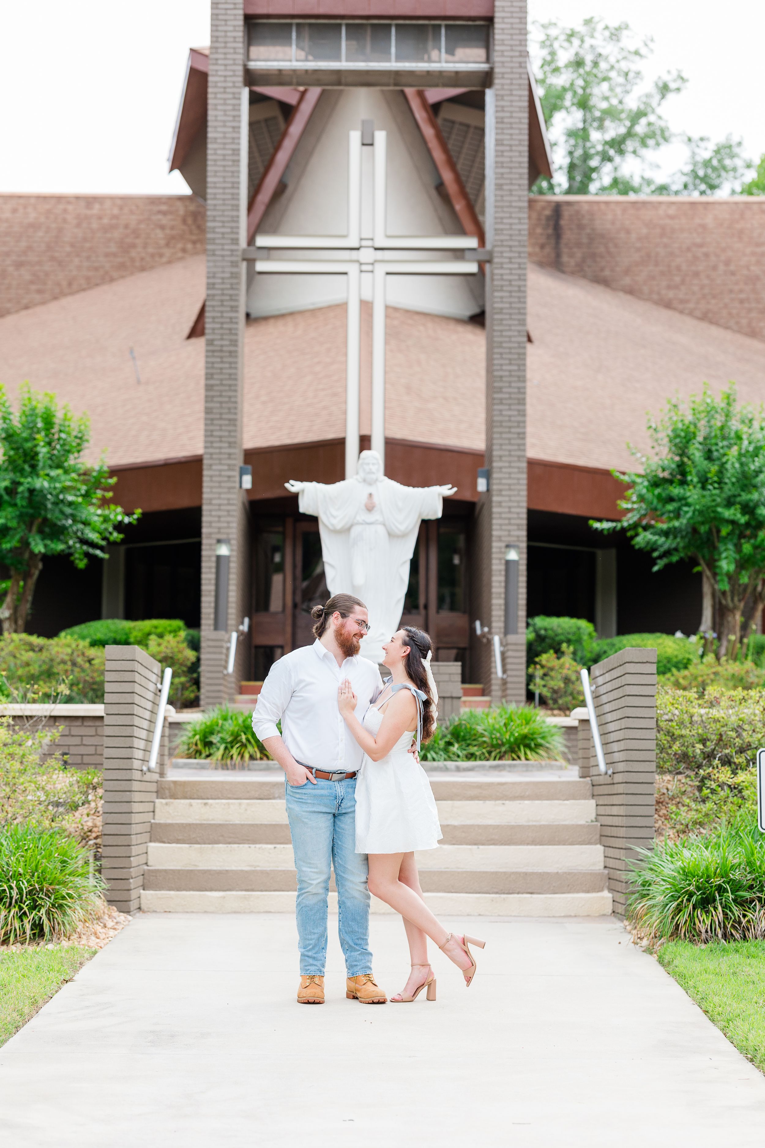 Romantic moment captured outside a modern brick church entrance with landscaping.