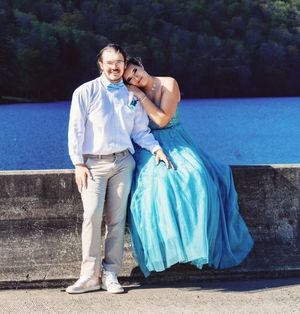 A romantic lakeside photo session featuring a couple in formal wear on a concrete platform.