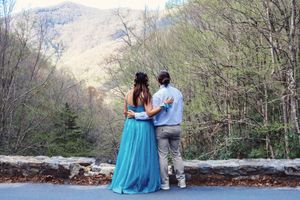 A couple shares intimate moments during a mountain photoshoot with fall foliage in the background.
