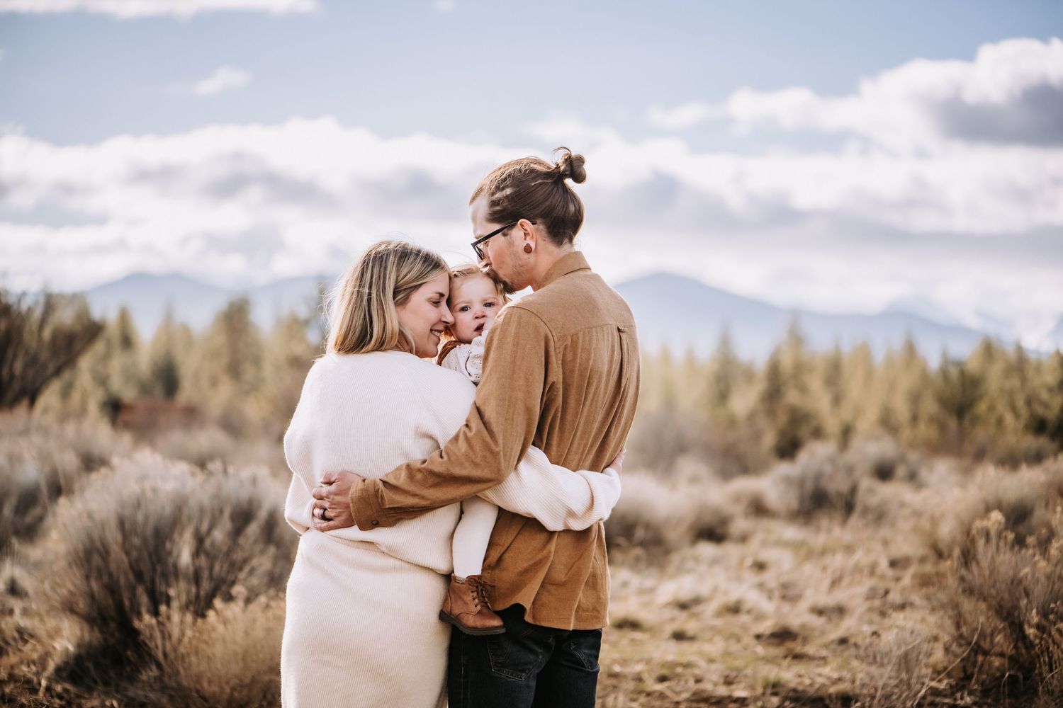 Romantic couple embracing in a rustic outdoor setting with mountains in the background.