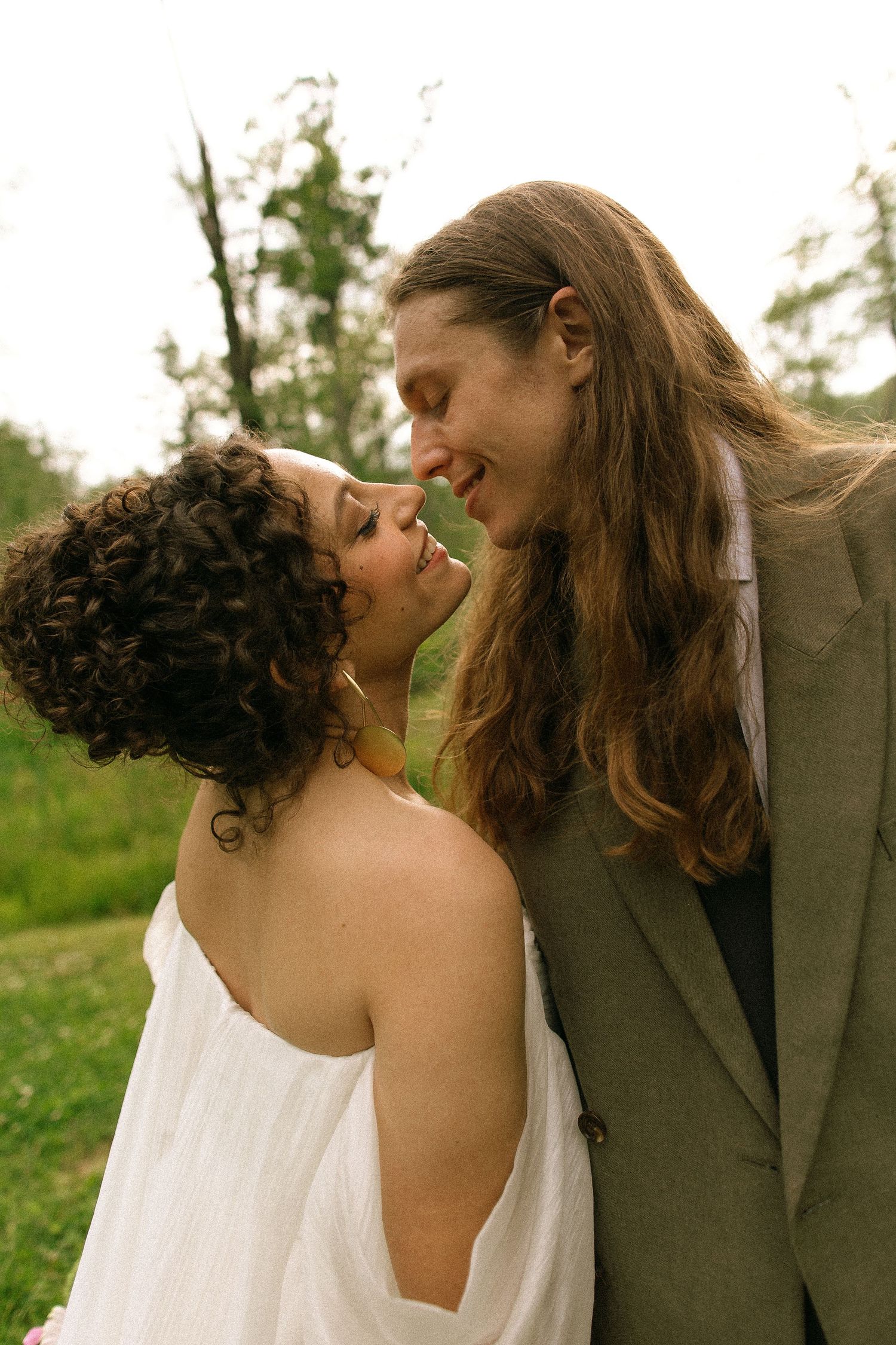 A joyful wedding couple sharing a moment against a stone wall backdrop.