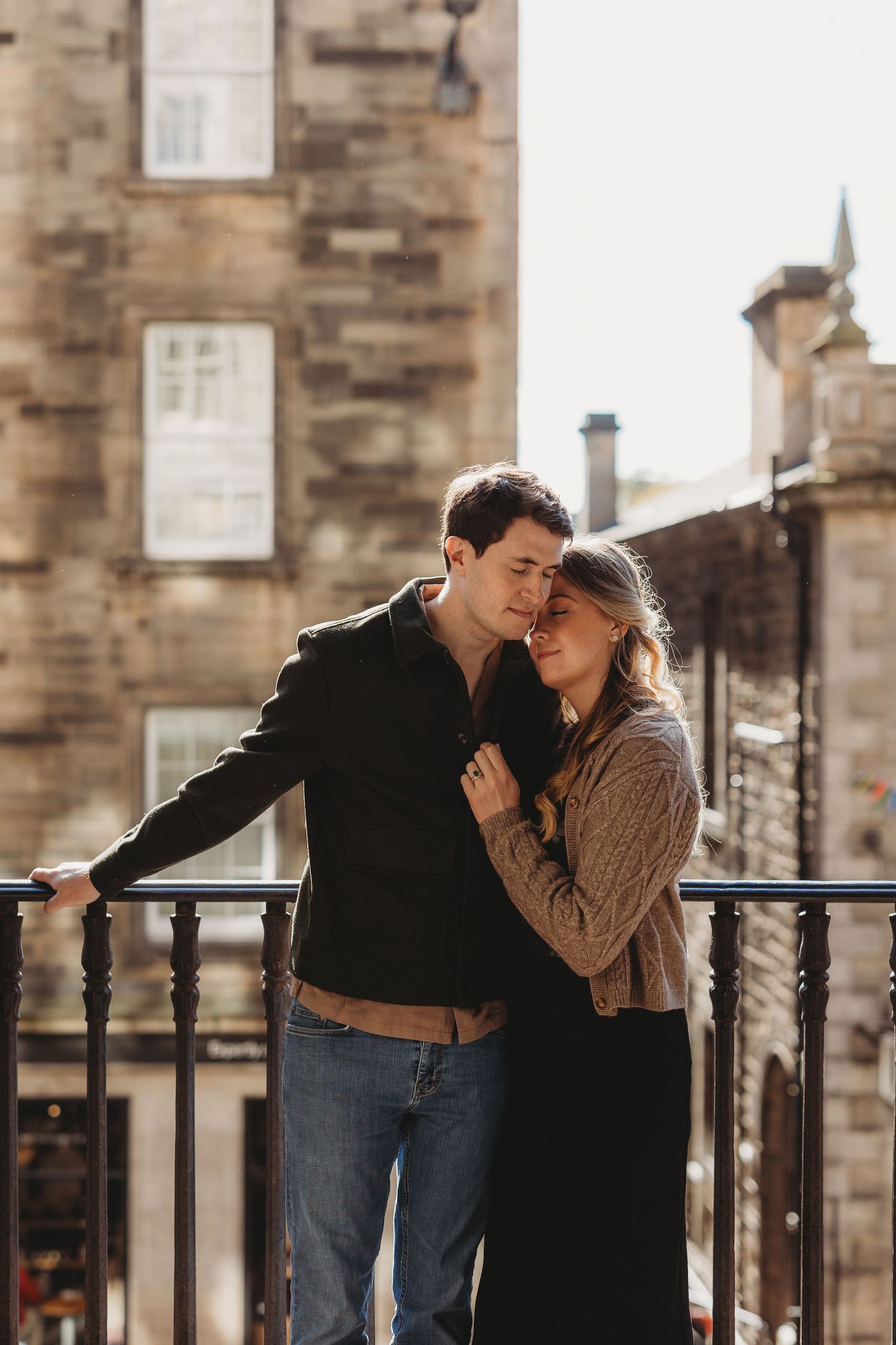 Stylish couple sharing intimate moment on urban street with mountain backdrop.