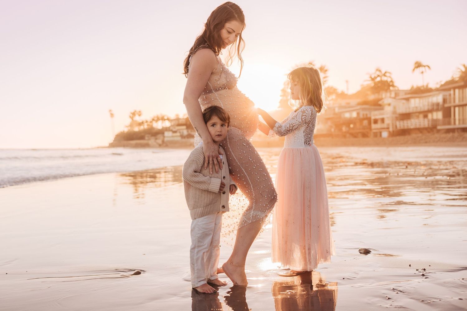 A family enjoying a sunset moment together on the beach with golden light illuminating their silhouettes.