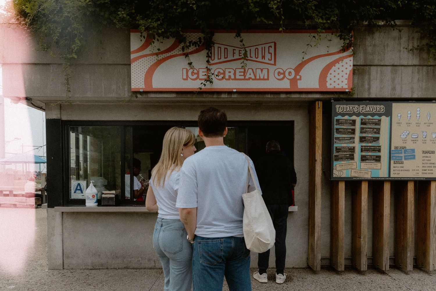 Engaged Couple standing together at an outdoor ice cream stand ordering treats on a sunny day. Brooklyn New York Miranda Photo & Co