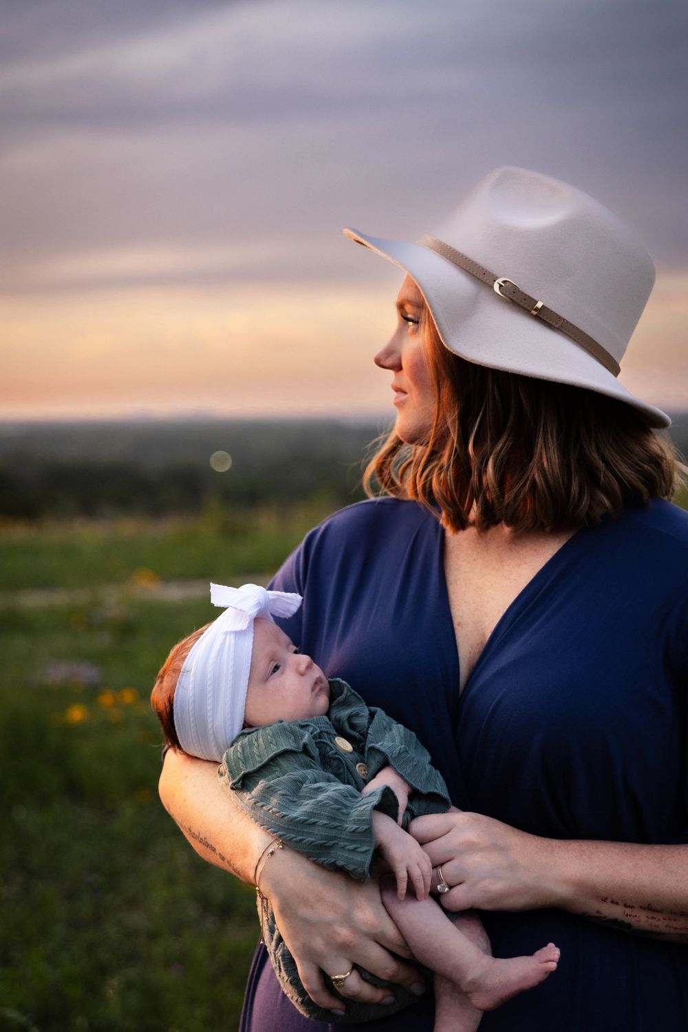 A woman holds her baby in a beautiful outdoor setting.