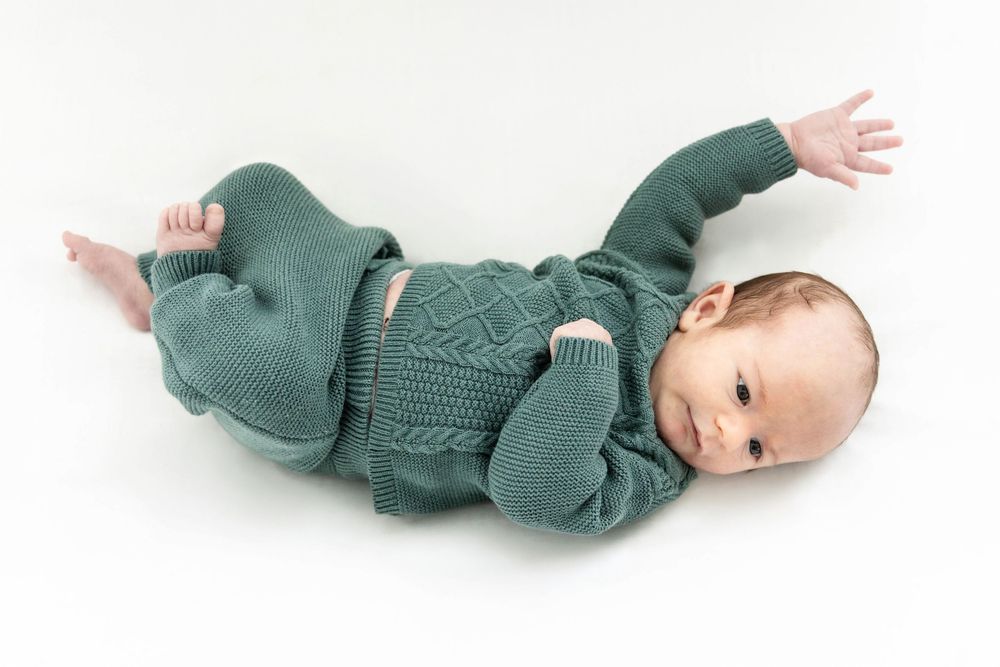 A newborn baby laying in a white crib. Lifestyle Newborn style.