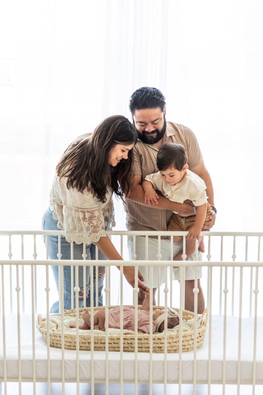 A family admires the baby in the white crib.