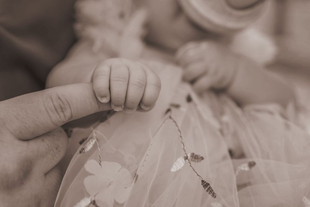 A close up of a baby holding their Dad's finger.