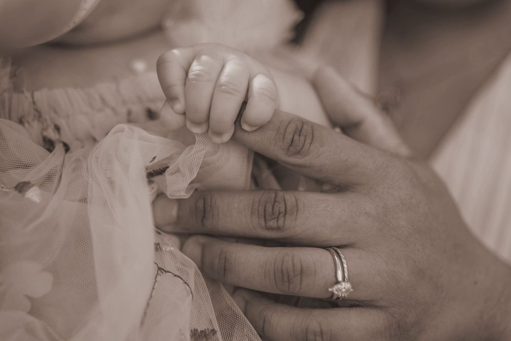 A close up of a baby holding their Mom's finger.