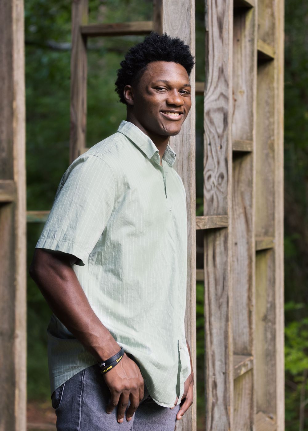 Casual outdoor portrait against wooden structure in natural lighting.