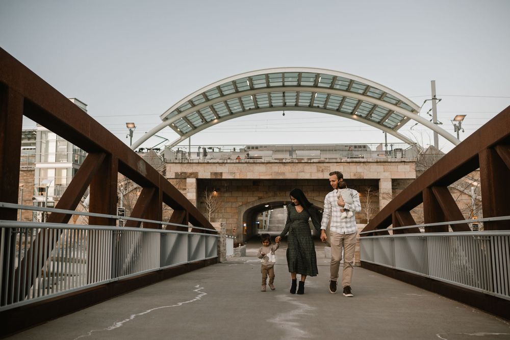 A couple walking together on an urban bridge with an arched glass ceiling overhead.