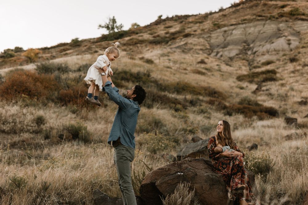 A loving moment captured outdoors with a family sitting by a fallen log in nature.