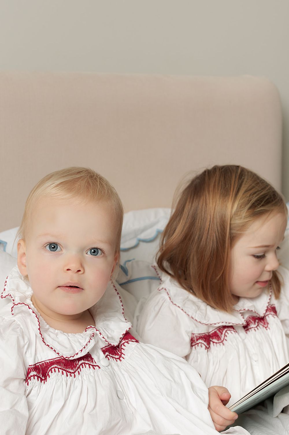London, UK, family photography session, sisters wearing matching Smock London night dresses, sitting together while reading a book.