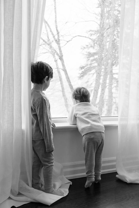 In home family photography session. Playful moments in the flowing white curtains by the window.