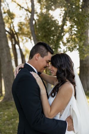 Intimate wedding moment captured between couple in wooded setting with natural light.