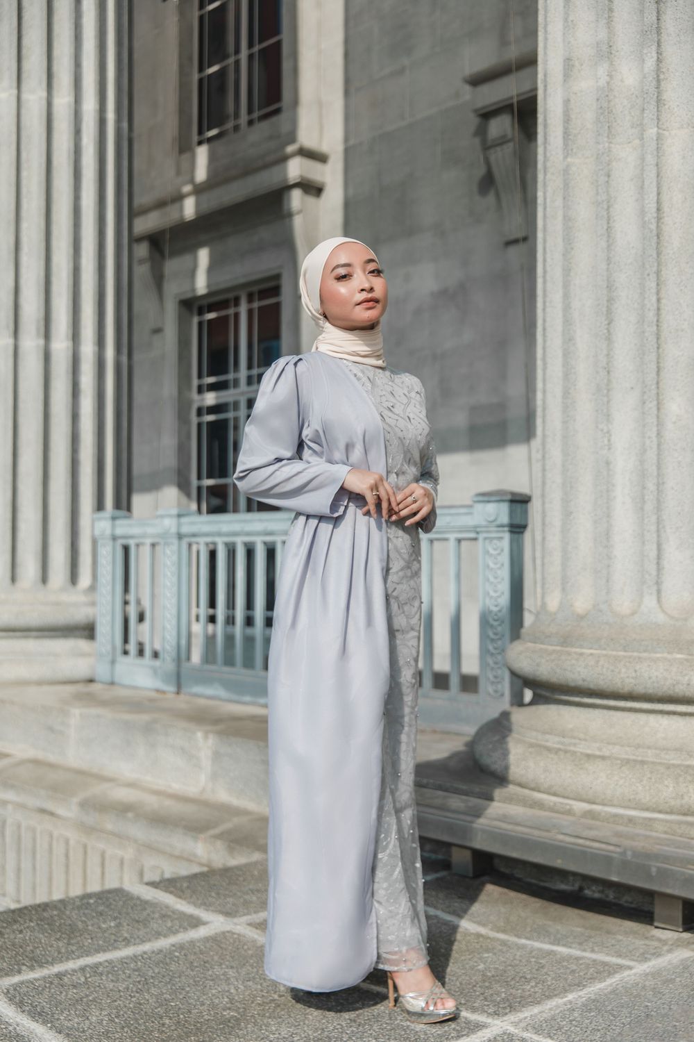Elegant grey abaya outfit styled against classic architectural columns.