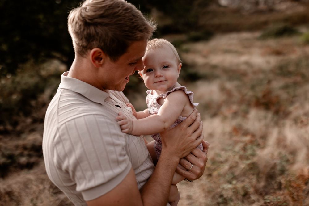 Tender family moment captured in warm sepia tones against a natural outdoor backdrop.