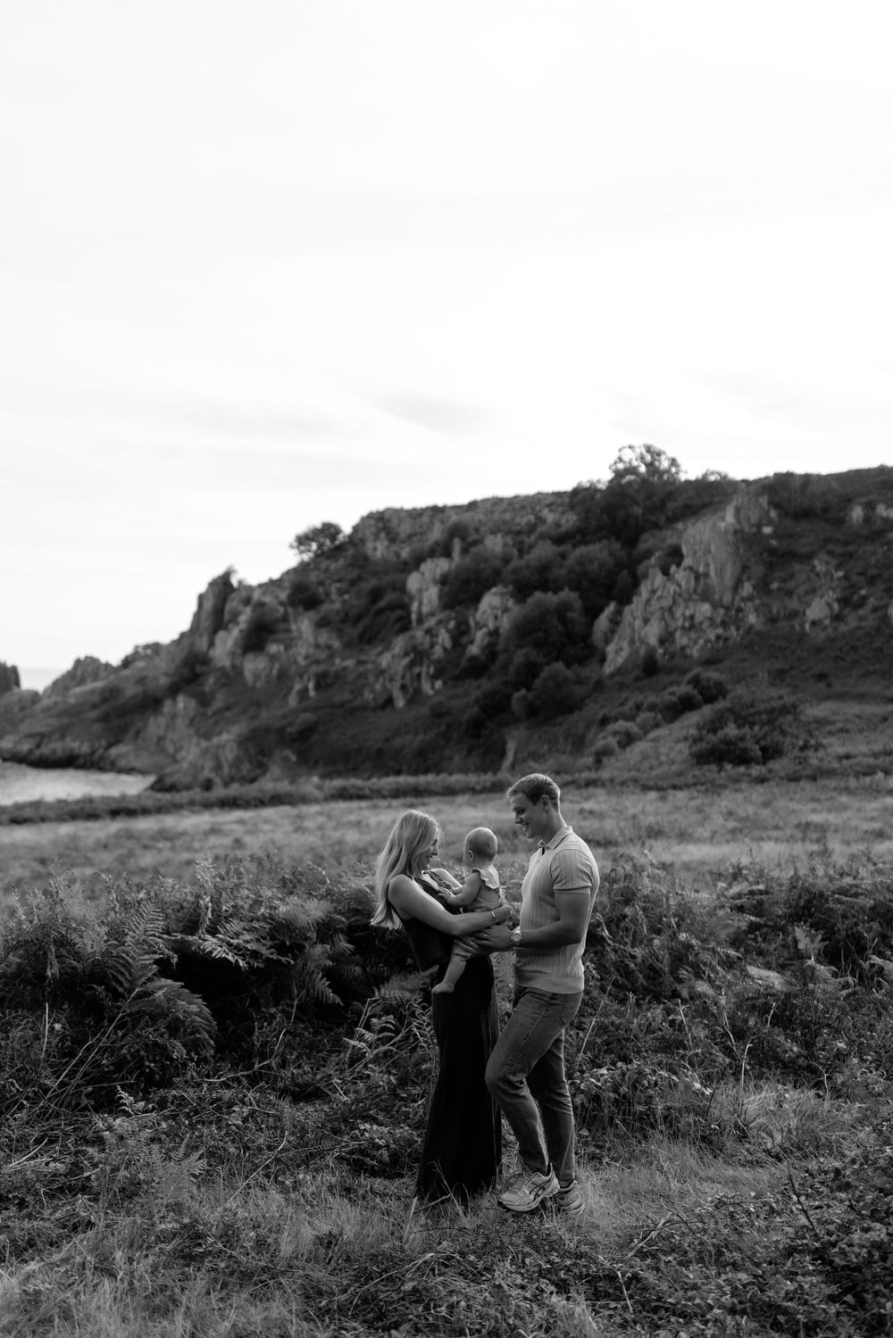 Silhouetted figures embrace on a hillside path during sunset.