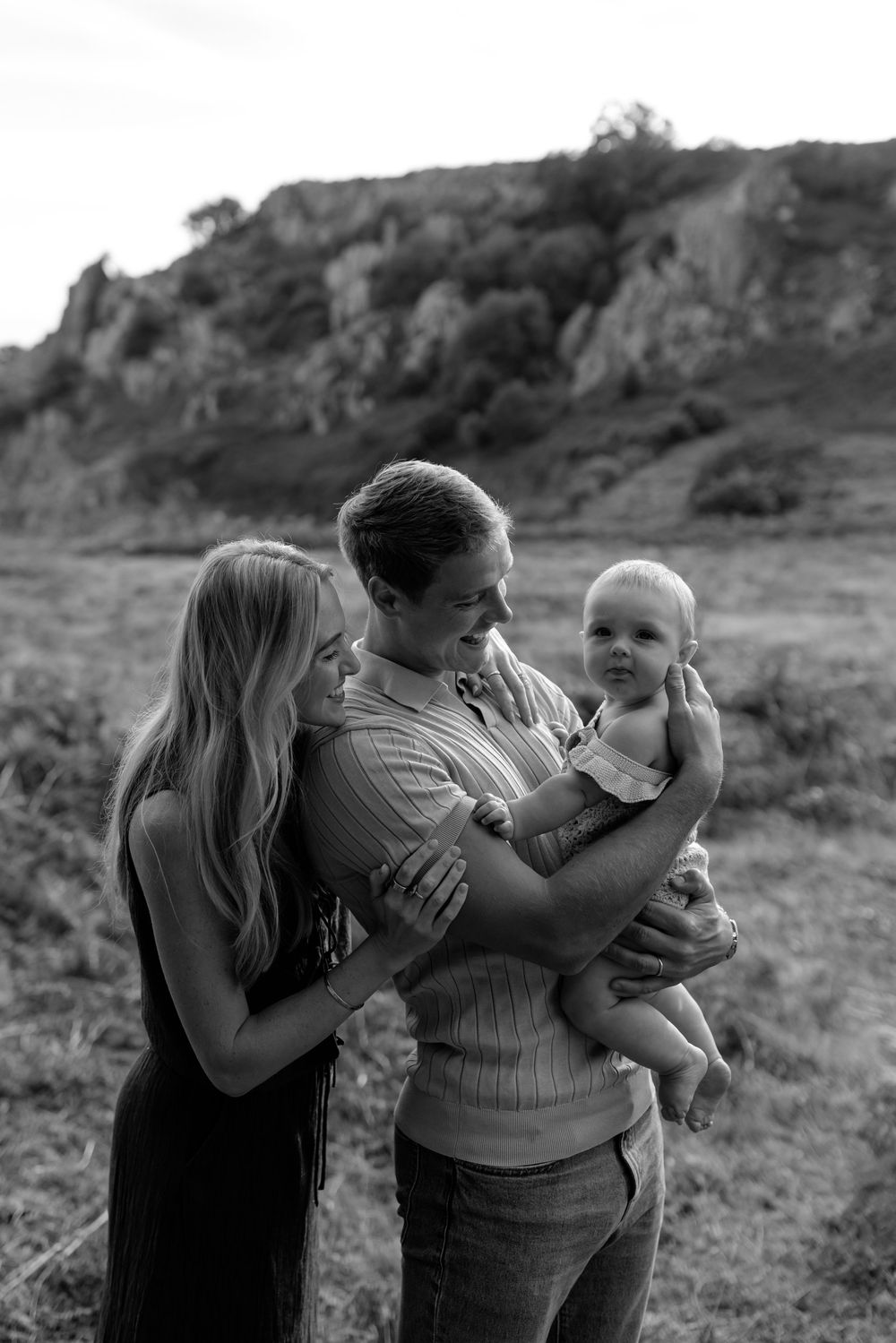 Family sharing intimate moments together against rocky natural landscape.