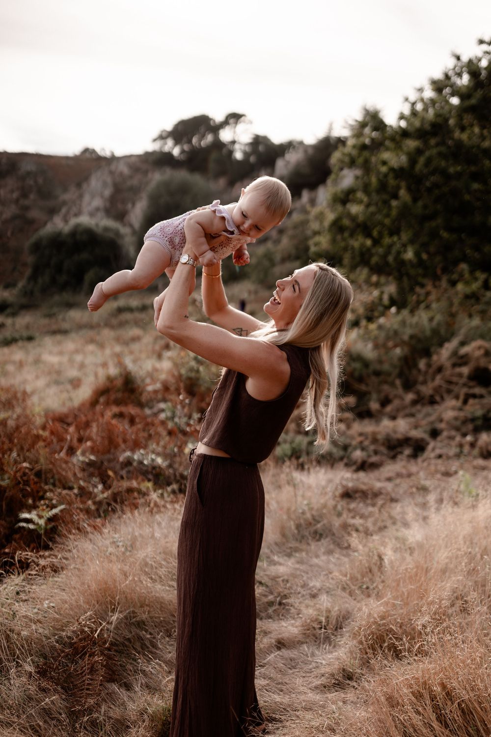 Tender moments unfold during a sunset photoshoot in tall grass.