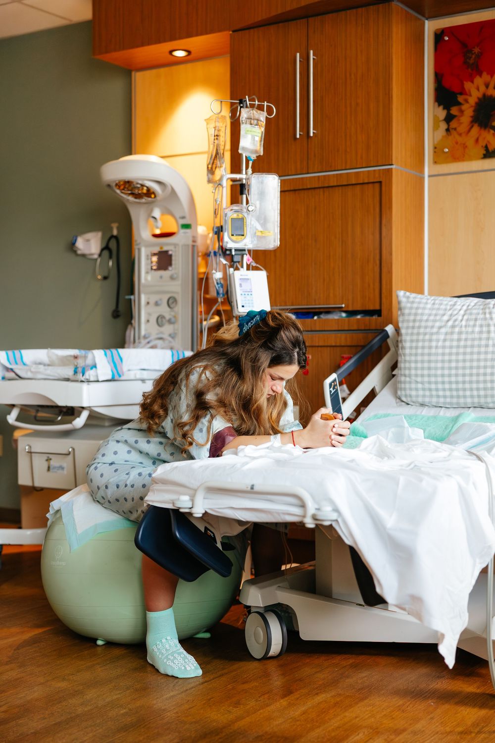 Patient resting in hospital bed with medical equipment and monitors visible in warm-lit hospital room.