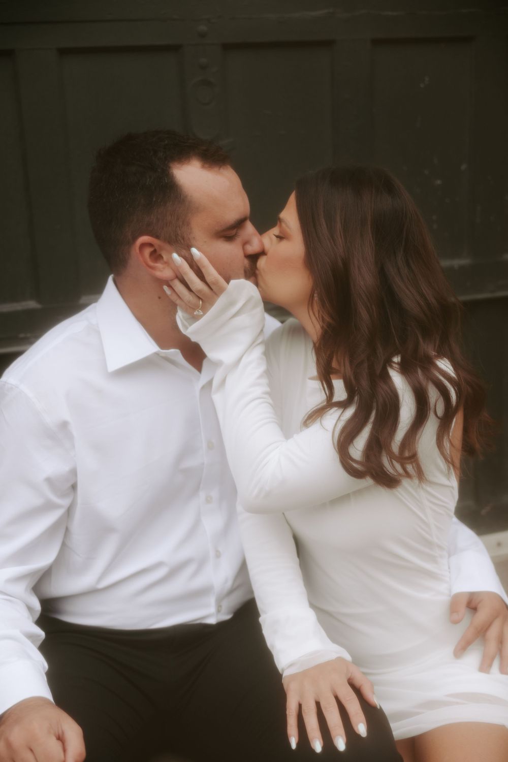 A romantic moment captured between a couple in white attire.