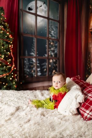 A series of three photos showing a baby in festive green clothing resting on white fur with Christmas decorations visible.