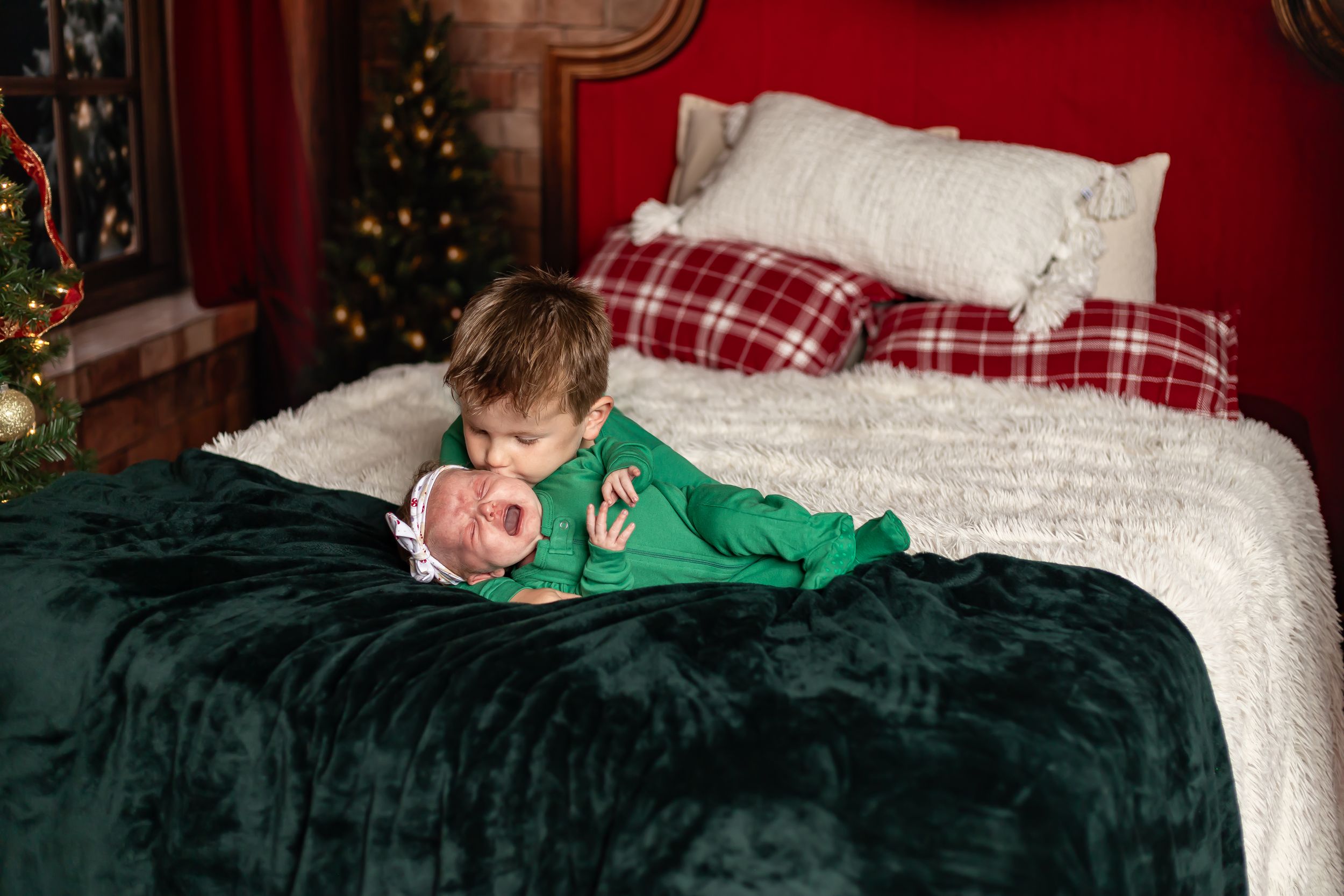 A cozy Christmas scene shows someone sleeping on bedding with festive decor and a Christmas tree in the background.