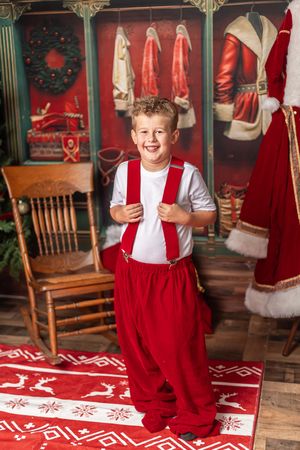 A festive holiday photo scene with wooden chairs and red and white Nordic pattern rugs in a decorated setting.