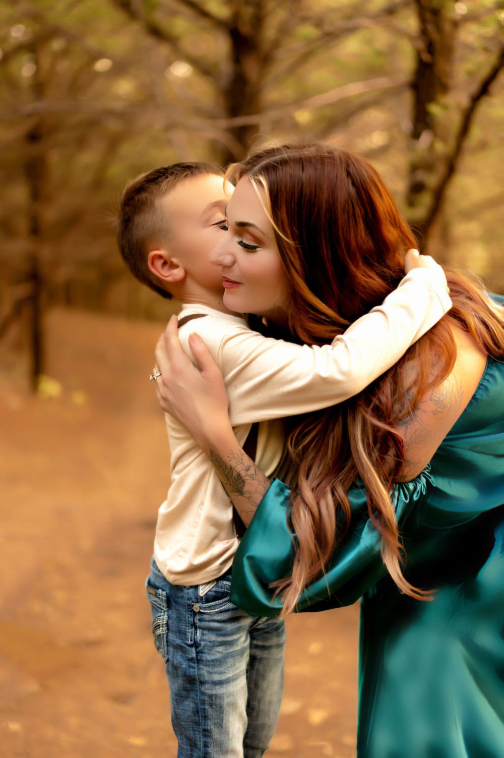 A tender moment captured in autumn shows affectionate embrace between parent and child in a forest setting.