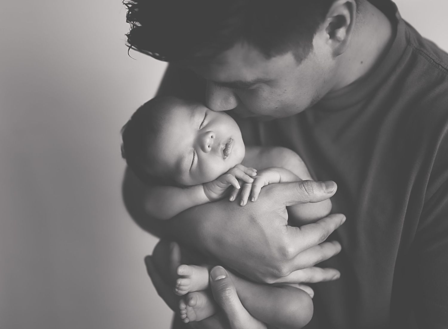 Daddy holding baby boy to chest and taking him all in BEST NEWBORN PHOTOGRAPHER