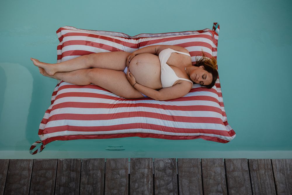 Femme enceinte dans une piscine en seance photo grossesse a domicile a Lille. Jeu de couleurs, lumiere et texture pour sublimer la maternite