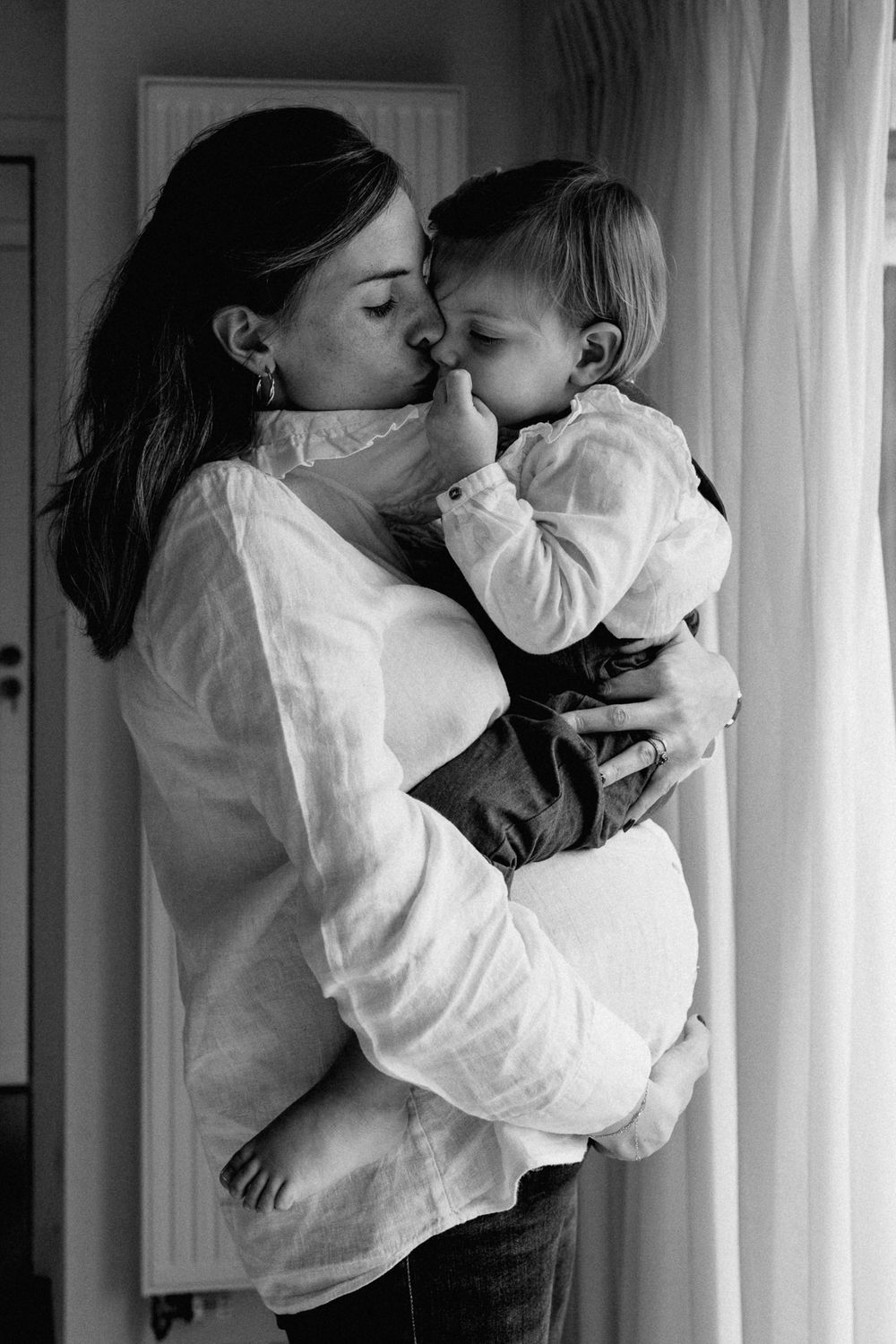 femme enceinte portant son aine en seance photo grossesse en famille a domicile a Lille : une image douce et puissante a propos des liens