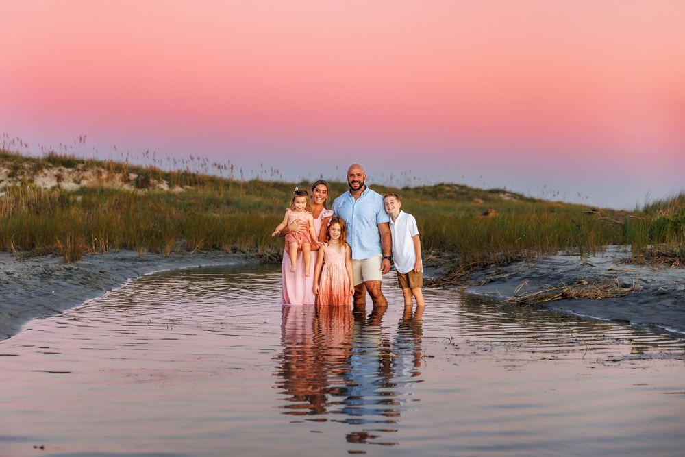 A family session captured by Samantha Ann Photography at Wrightsville Beach during a vibrant pink sunset.