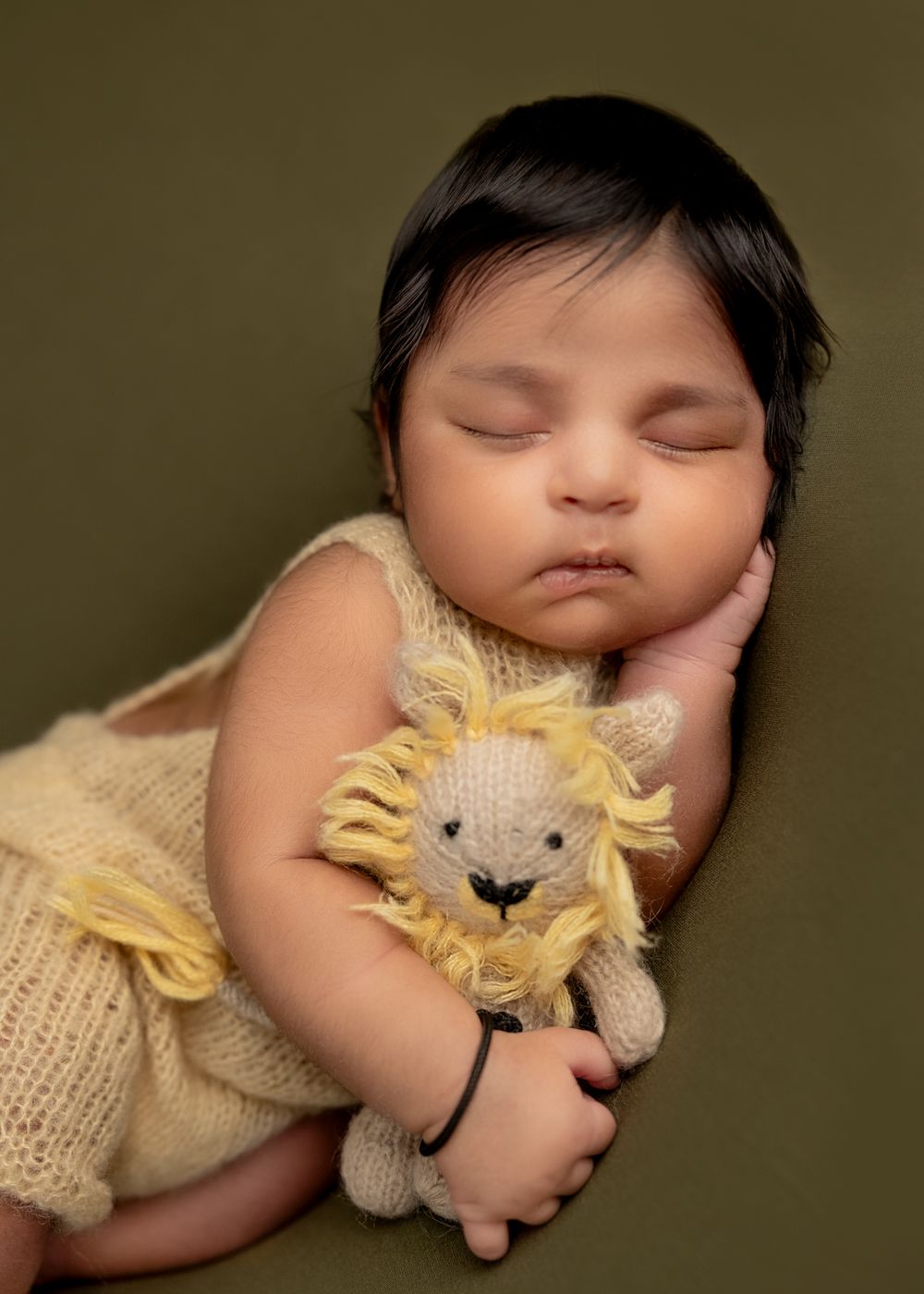 A sleeping baby snuggling with a knitted cream-colored cat plush toy in a series of tender moments.