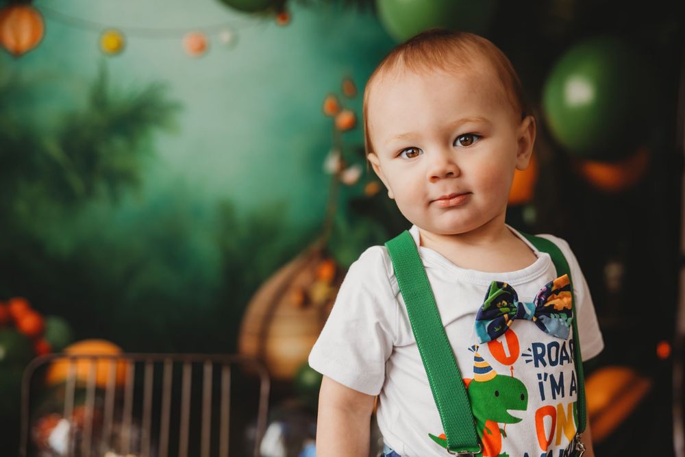 Baby in festive outfit surrounded by pumpkins and autumn decorations.