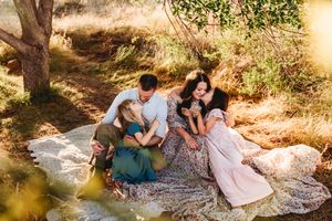 Group sitting together on blanket enjoying peaceful afternoon in nature during golden sunlight.