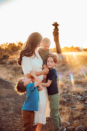A family embraces in a loving moment at sunset in a desert landscape with golden light streaming through.