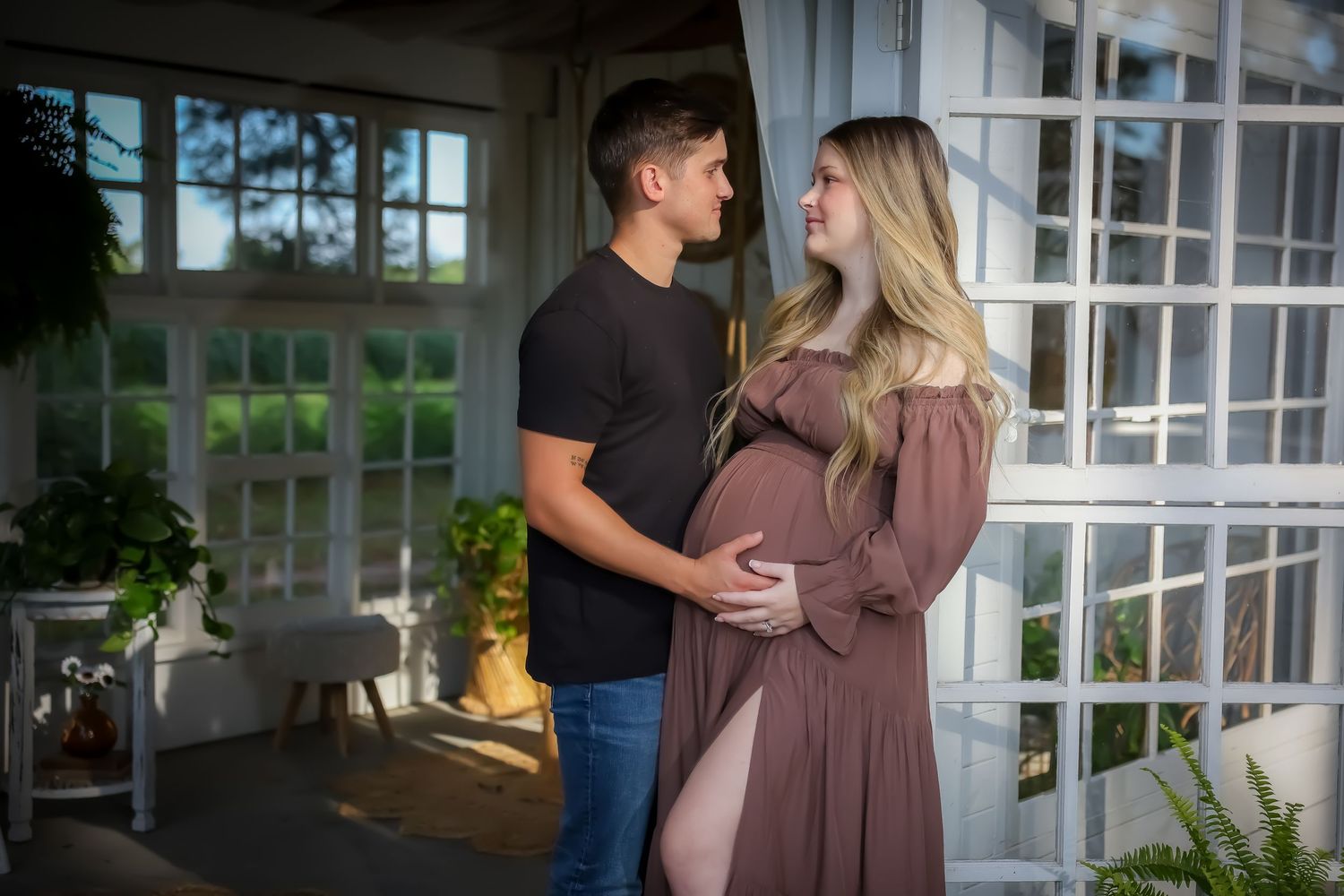 Maternity lifestyle session in sunlit room with white windows.
