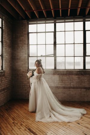 A stunning bridal portrait in a rustic brick loft with large industrial windows and hardwood floors.