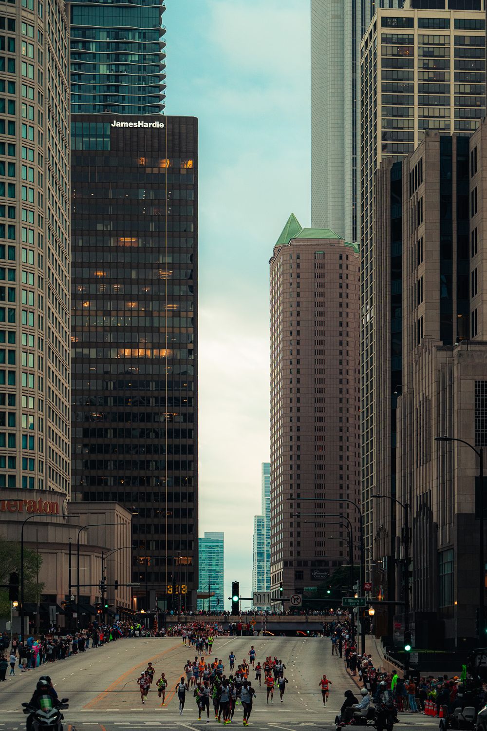 Urban cityscape with tall skyscrapers framing runners on Chicago street during marathon.